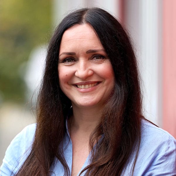 Porträt der lächelnden Aristi Dimou mit langen dunklen Haaren.