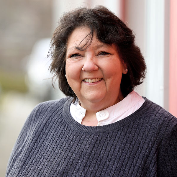 Porträt von Birgit Struck, die freundlich lächelnd in einem grauen Strickpullover posiert.