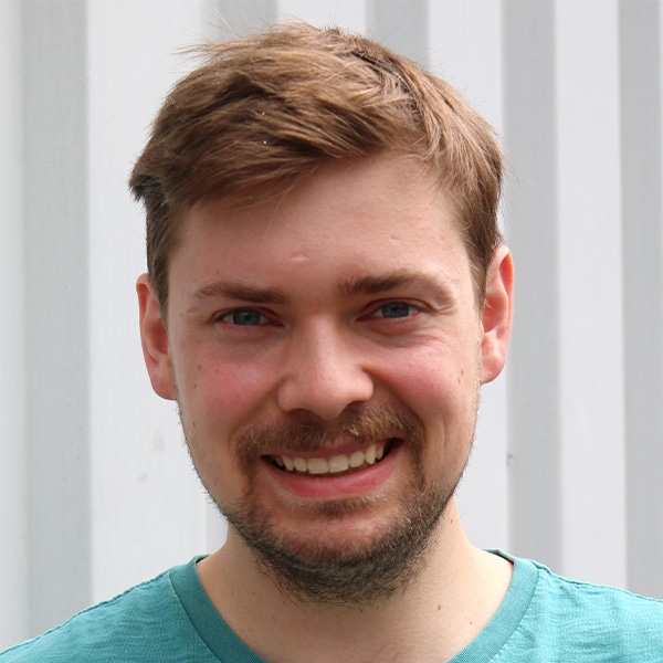 Porträt von Daniel Finke, ein lächelnder Mann mit Bart und kurzem braunem Haar.