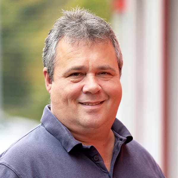 Porträt von Werner Graumüller, ein lächelnder Mann im blauen Poloshirt.